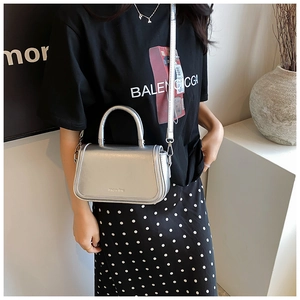 Détail du sac bandoulière argenté avec finition métallique brillante et poignée haute