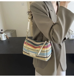 Detail of bohemian straw cylinder bag with colorful stripes and gold chain strap