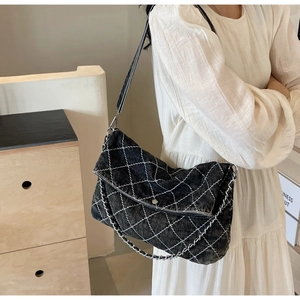Dettaglio borsa a tracolla in denim nero lavato con trapuntatura a rombi e catena metallica