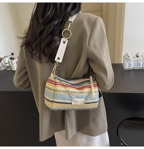 Close-up of a colorful woven rainbow bag with white leather strap and gold hardware