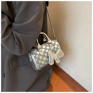 Detail of checkered weave pillow bag with silver dog charm and metal handle
