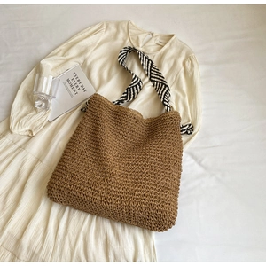 Close-up of deep brown straw tote bag with black and white striped woven straps