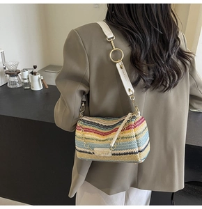Detail of colorful bohemian woven barrel bag featuring white leather strap and gold chain