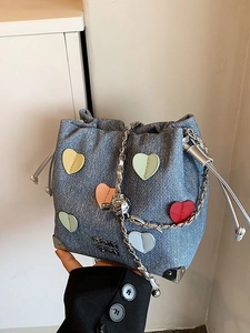 Blue denim drawstring bucket bag with colorful heart patches and silver chain strap