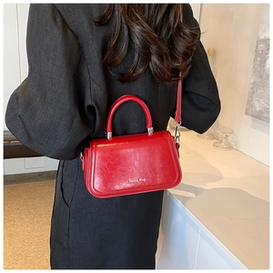 Vue latérale d'un sac à bandoulière en cuir rouge brillant porté avec boucle en argent