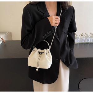 Détail du sac seau crème avec boucle papillon, breloques perles et chaîne en argent