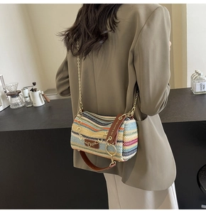 Detail of colorful striped woven straw bucket bag with gold chain and leather strap