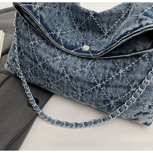 Dettaglio borsa tote in denim trapuntato con tracolla a catena e chiusura a scatto
