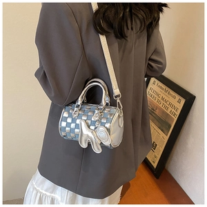 Detail of silver checkerboard barrel bag with animal charm and adjustable strap