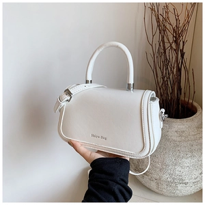 Vue détaillée d'un sac à bandoulière blanc minimaliste en cuir avec poignée et logo