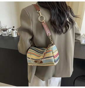 Close-up of bohemian woven straw bag with multi-color stripes and leather shoulder strap