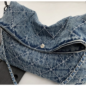 Dettaglio ravvicinato della trama denim blu trapuntata e catena d'argento con fibbia