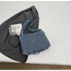 Dettaglio della borsa tote in denim blu con motivo a rombi trapuntati e tracolla larga