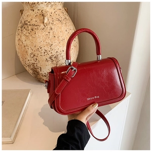 Sac à bandoulière minimaliste en similicuir rouge sur un socle géométrique moderne