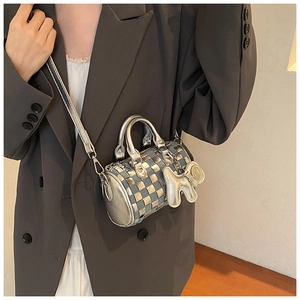 Detail of silver metallic and blue woven mini cylinder bag with cute dog charm