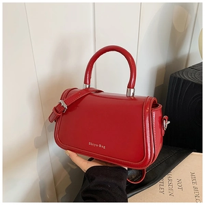 Détail du sac à main rouge en cuir verni brillant avec finitions argentées et poignée