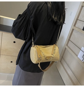 Detail of bohemian woven cylinder bag with gold chain strap on a model shoulder