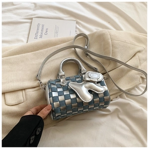 Detail of checkered denim pillow bag with silver rabbit charm and leather weaving