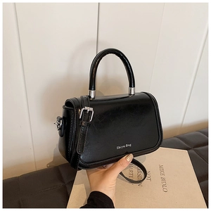 Détail d'un sac à bandoulière en cuir noir texturé avec finitions argentées et poignée