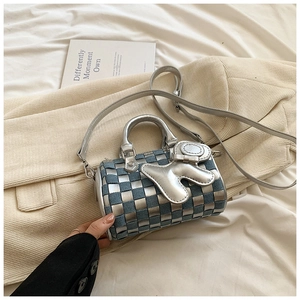 Detail of blue denim and silver checkerboard pillow bag with a heart charm accessory