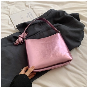 Vue détaillée du sac à chaîne rose métallisé sur un blazer gris et des draps
