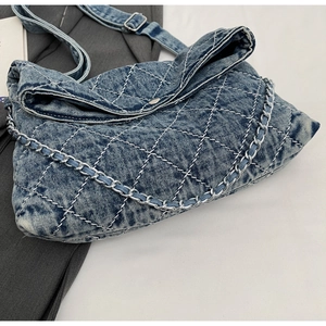 Dettaglio della borsa tote in denim trapuntato con catena argento e chiusura magnetica
