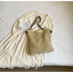 Detailed close-up of straw woven tote bag featuring hollow texture and geometric shoulder strap