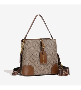 Detailed close-up of a vintage canvas bucket bag with leather base and wide jacquard strap