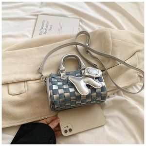 Macro detail of a cylinder woven handbag in silver metallic and blue denim with metal charm