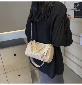 Detail view of woven cylinder crossbody bag with rainbow chain and white leather strap
