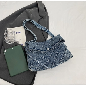 Dettaglio della borsa a tracolla in denim blu con motivo a rombi e catena in argento