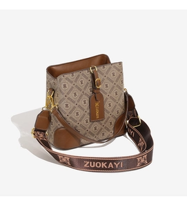 Detail of printed bucket bag showing gold-tone hardware and adjustable logo strap