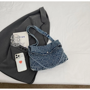 Dettaglio borsa a tracolla in denim blu con trapuntatura a rombi e catena argento