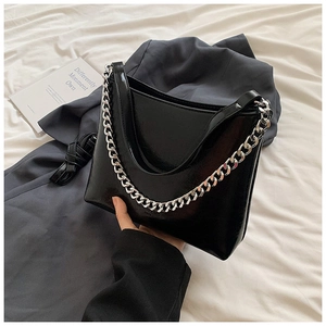 Détail d'un sac bandoulière en cuir noir brillant avec chaîne en métal argenté