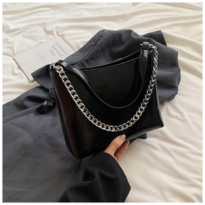 Détail d'un sac à main en cuir PU noir brillant avec chaîne argentée et texture