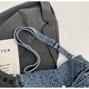 Dettaglio della borsa tote in denim blu con cuciture a rombi bianchi e tracolla regolabile