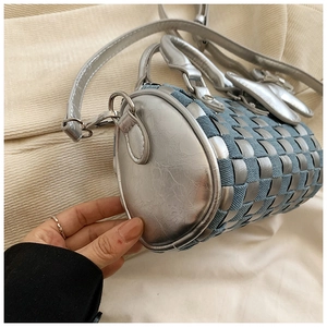 Detail of woven cylinder bag featuring silver leather and blue denim texture with hand