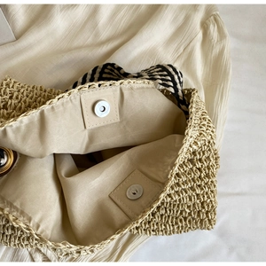 Detail view of woven straw tote bag with silver magnetic clasp and fabric lining