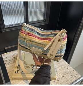 Detail of bohemian rainbow straw bag featuring cotton woven stripes and gold floral chain