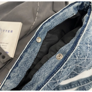 Dettaglio della borsa in denim blu con trapuntatura a rombi e bottoni a pressione argento