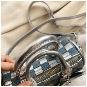 Close-up of checkered denim and silver mini cylinder bag with metallic handles