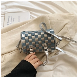 Close-up of checkerboard cylinder bag in blue denim and metallic silver weaving