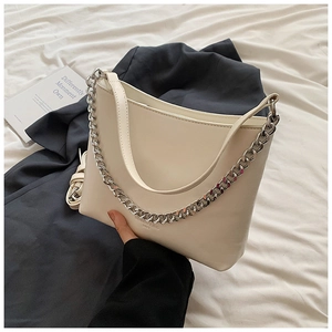 Détail du sac seau en cuir crème avec chaîne argentée et gaufrage de la marque