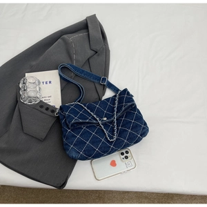 Dettaglio borsa tote in denim blu con trapuntatura a rombi e catena argentata