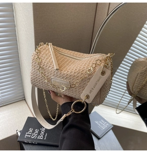 Detail of bohemian straw pillow bag with gold floral chain and leather strap