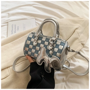 Close-up of checkered denim pillow bag with silver elephant charm and metallic handle