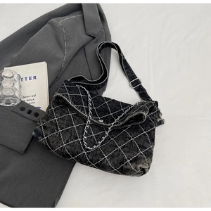 Dettaglio della borsa in denim nero con trapuntatura a rombi e catena argentata