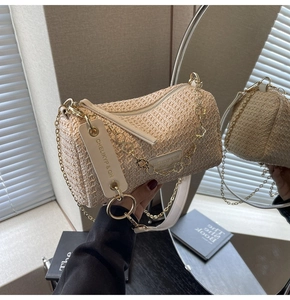 Detail of bohemian straw barrel bag featuring leather trim and metallic chain strap