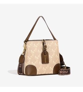 Detail view of the beige horse-print bucket bag with leather trim and wide shoulder strap