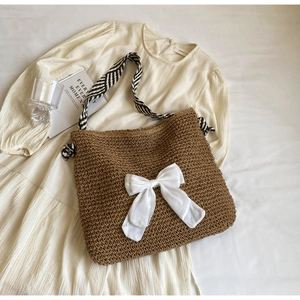 Detailed shot of large straw tote with white bow and geometric pattern strap